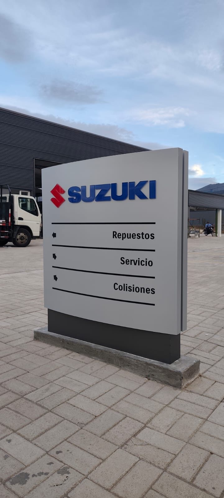 Tótem publicitario exterior Suzuki con señalética direccional